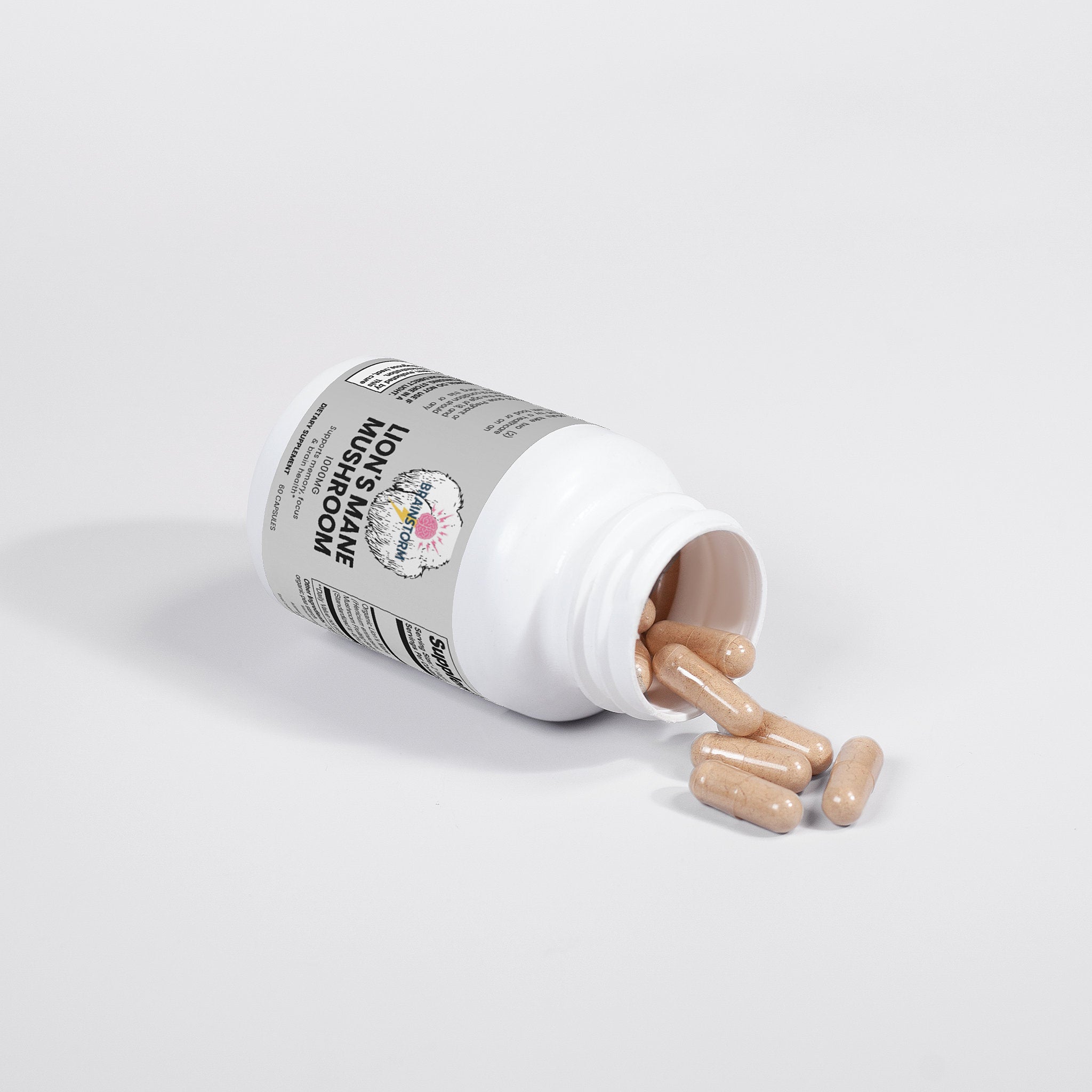 Supplement bottle labeled 'Lion's Mane Mushroom' by Brainstorm with Lion's Mane mushroom capsules spilling out of container on a white background