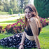 Woman sitting on grass in a park with flowers and trees in the background